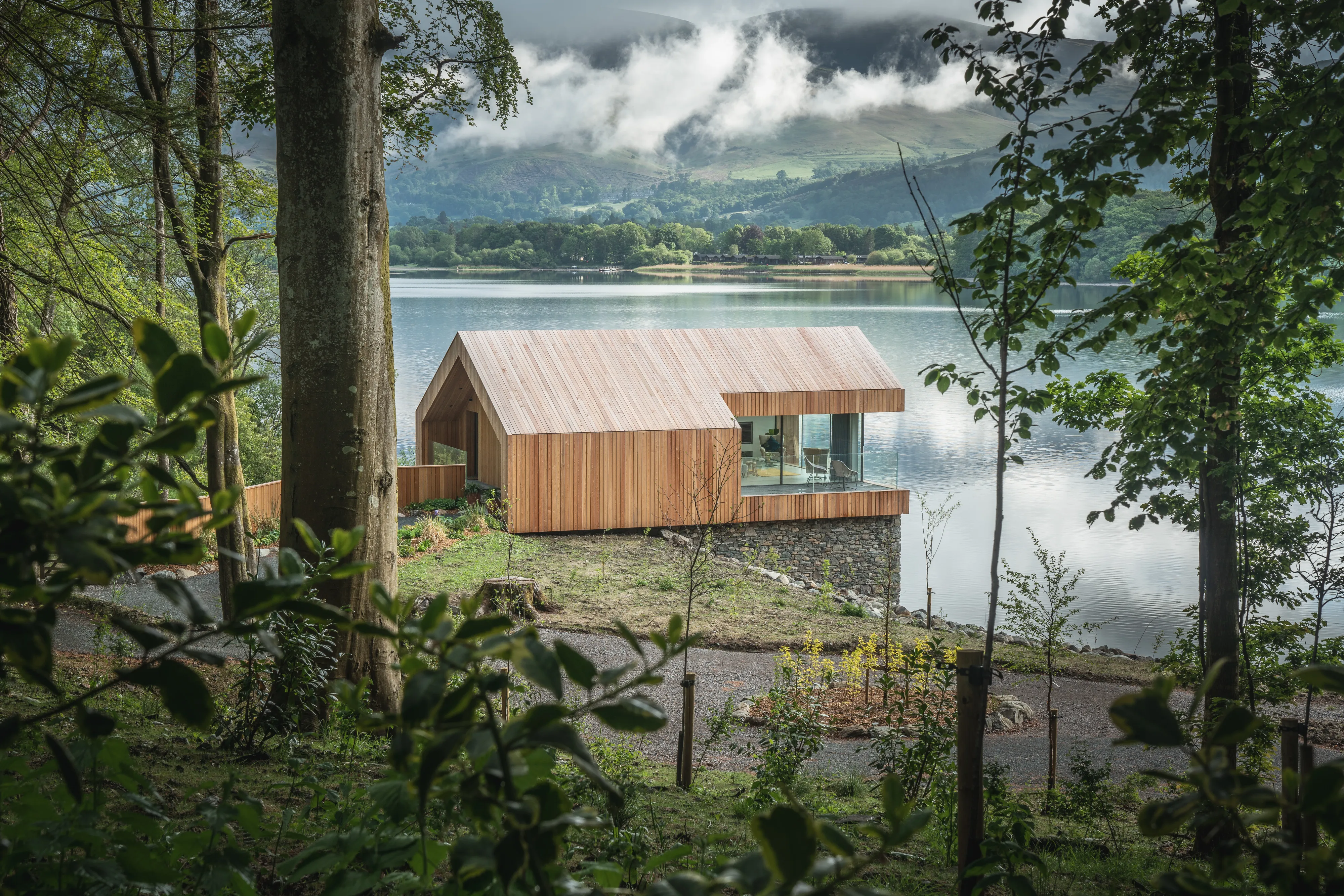 A timber cabin beside a lake, framed by trees